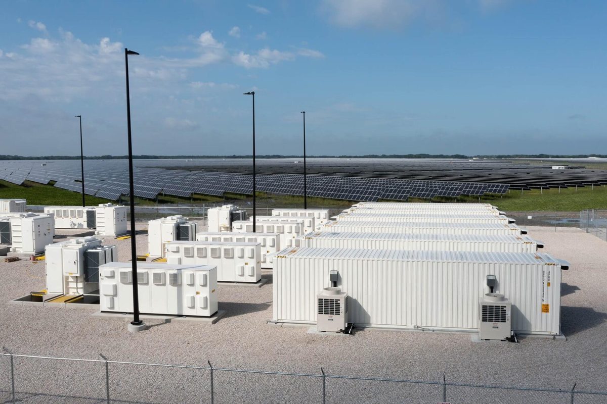 Conteneurs de batteries devant les rangées de panneaux de la centrale Lily au Texas
