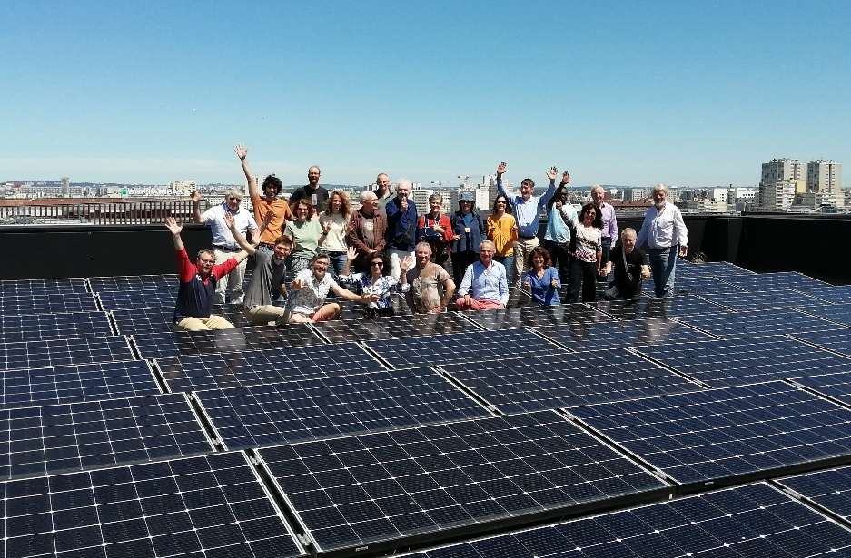 Un groupe de bénévoles d'Enercitif debout sur une toiture couverte de panneaux solaires à Paris