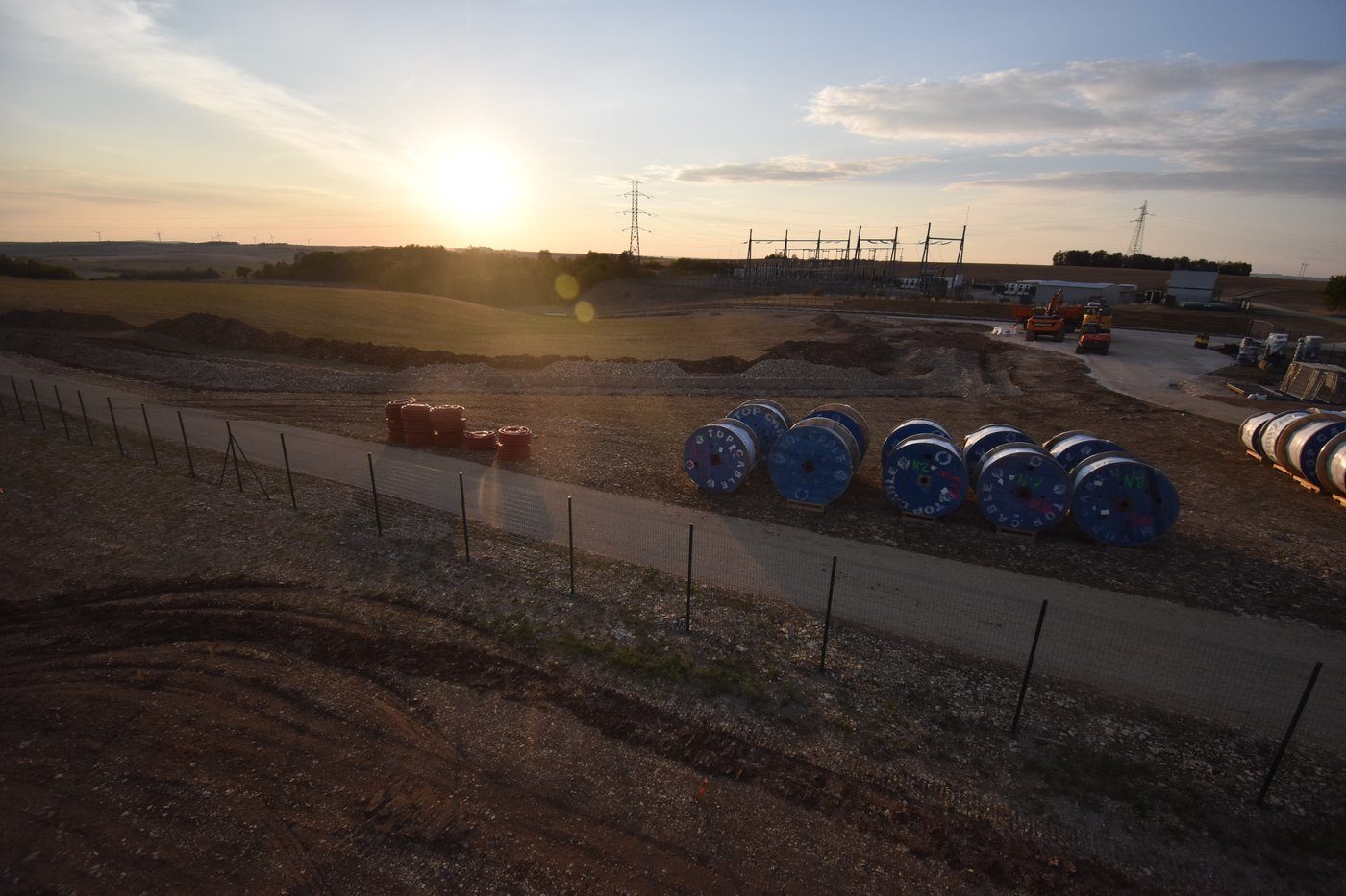 Chantier du parc solaire Grenier des Essences, tourets de câbles et poste électrique au soleil couchant