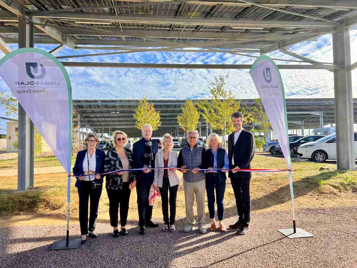 Sept personnes coupent un ruban tricolore sous des ombrières solaires de parking